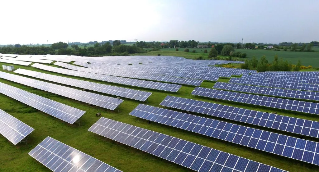 Pekerja memeriksa panel surya di atap gedung.